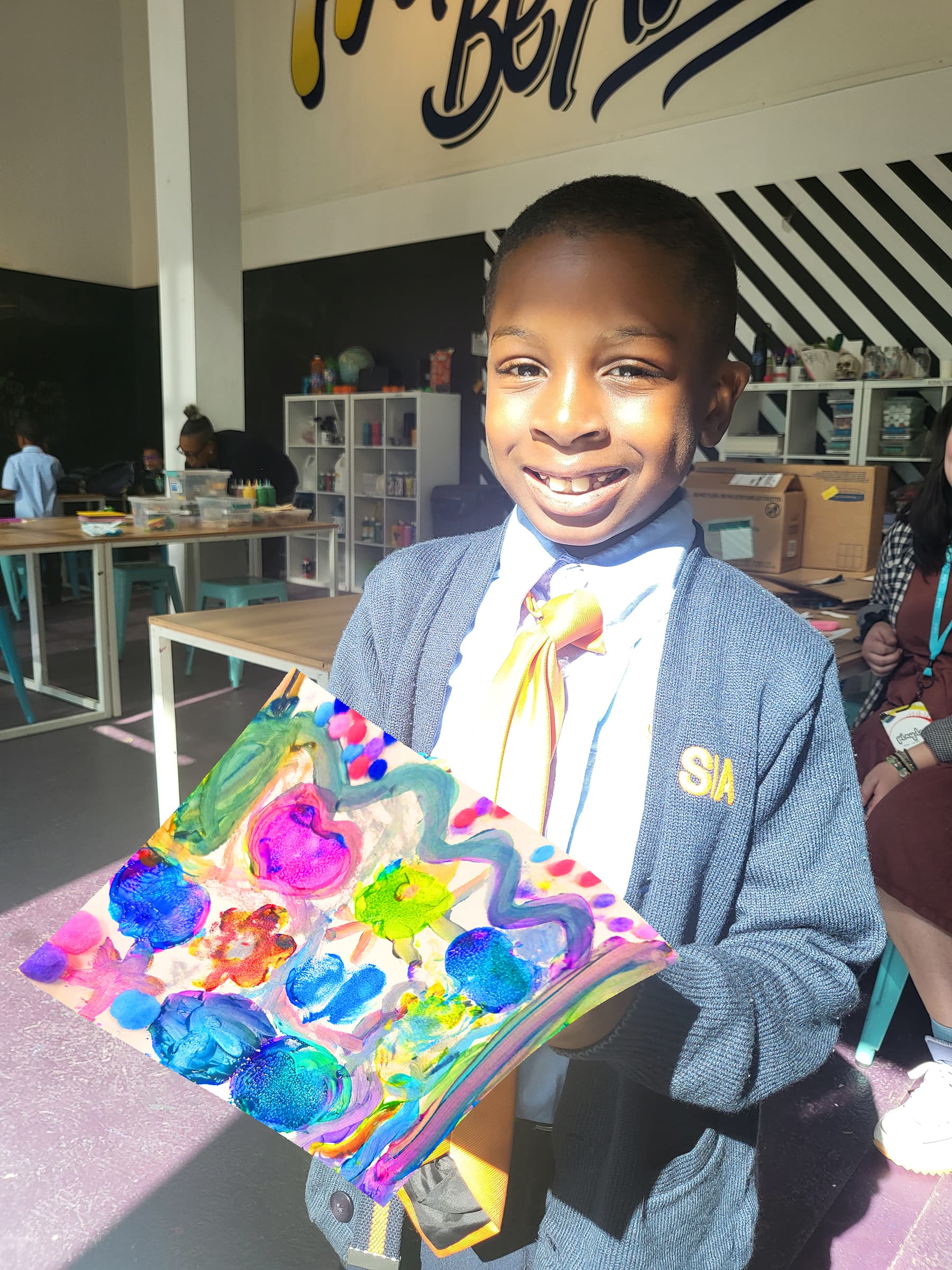 Kid proudly showing their artwork at Playday